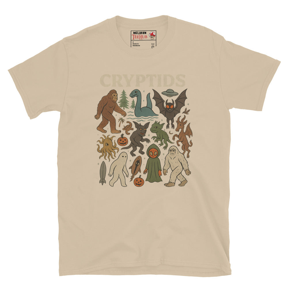 Sand T-shirt featuring vintage cartoon-style illustrations of various cryptids including Bigfoot, Mothman, Loch Ness Monster, and more.