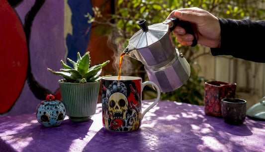 Hand pouring coffee into a glossy pop-culture mug on desk