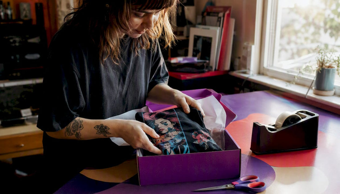 Hands packing t-shirt into shipping box