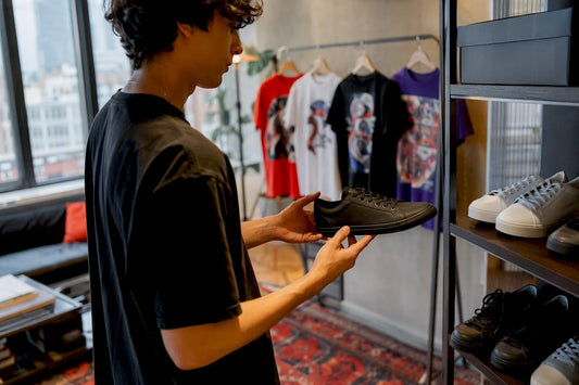 Hands holding sneaker near folded graphic tees