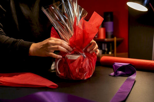 Hands wrapping a mug in colorful tissue