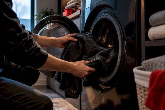 Hands placing an inside-out graphic tee in washer