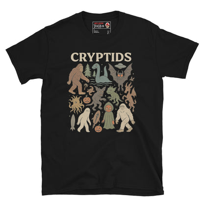 Black T-shirt featuring vintage cartoon-style illustrations of various cryptids including Bigfoot, Mothman, Loch Ness Monster, and more.