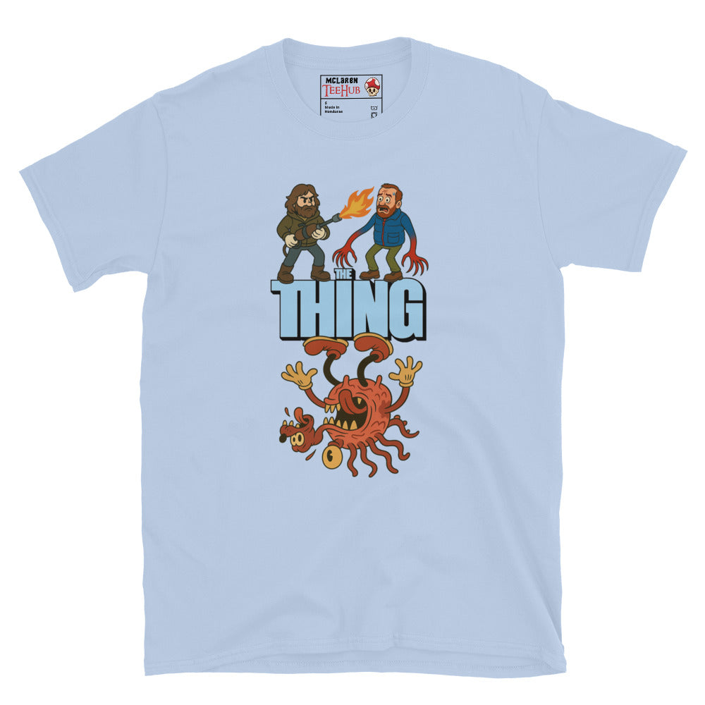Light blue T-shirt with a cartoon parody design of The Thing featuring MacReady with a flamethrower and a mutated creature.
