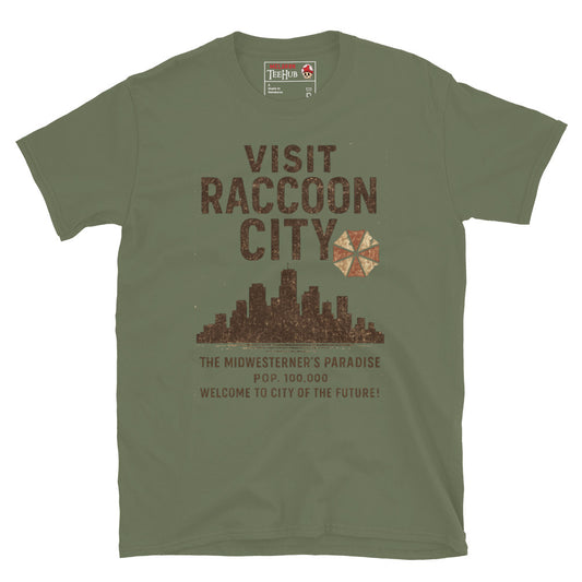 Military Green T-shirt with vintage-style “Visit Raccoon City” graphic featuring city skyline, Umbrella Corp logo, and distressed text inspired by Resident Evil.